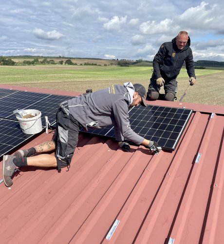 Solarteur befestigt PV-Modul auf einem Dach im Harz